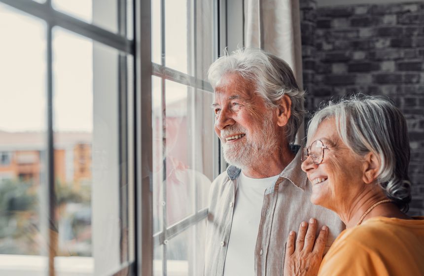 Couple de retraités regardant par la fenêtre de son logement